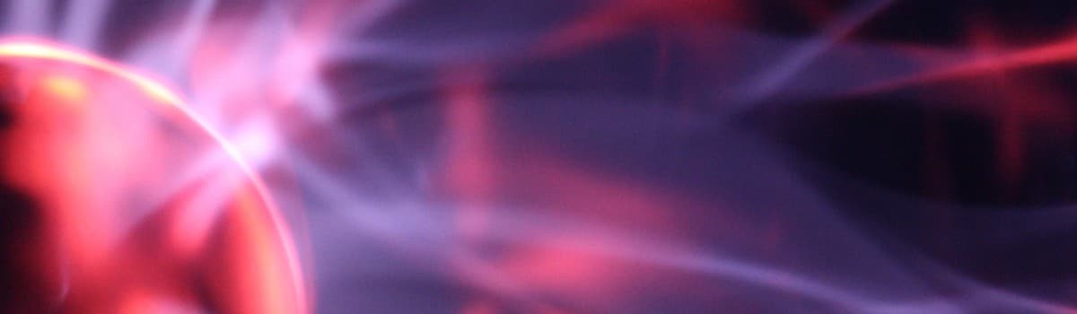 Abstract purple and pink smoke or light swirls on a dark background.