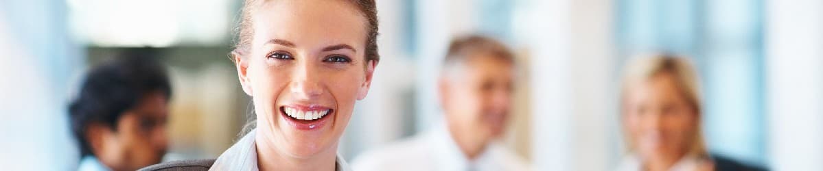 Smiling professional with colleagues in a bright office, representing teamwork and a positive work environment.