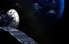 Satellite with solar panels and antenna against a dark background with Earth in the distance.