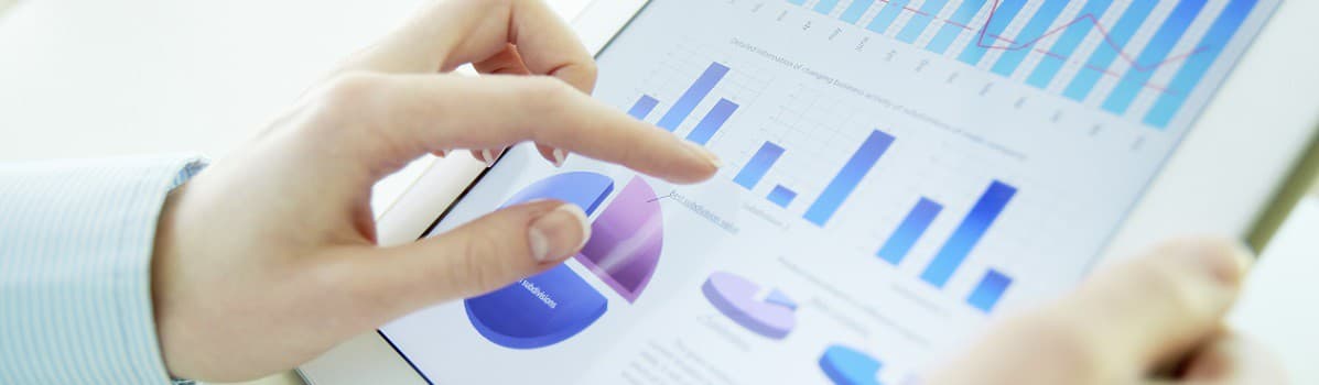 Hands interacting with charts and graphs, including bar and pie charts, on a tablet screen.