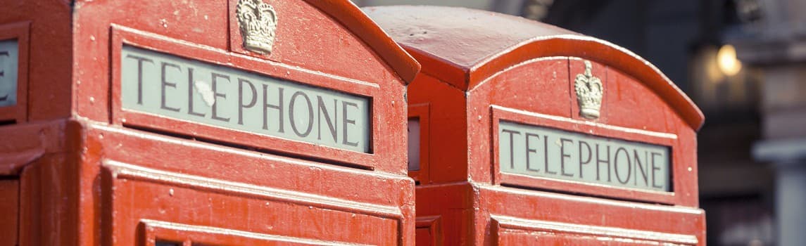 Two red British telephone booths with 'TELEPHONE' signs under a clear sky.