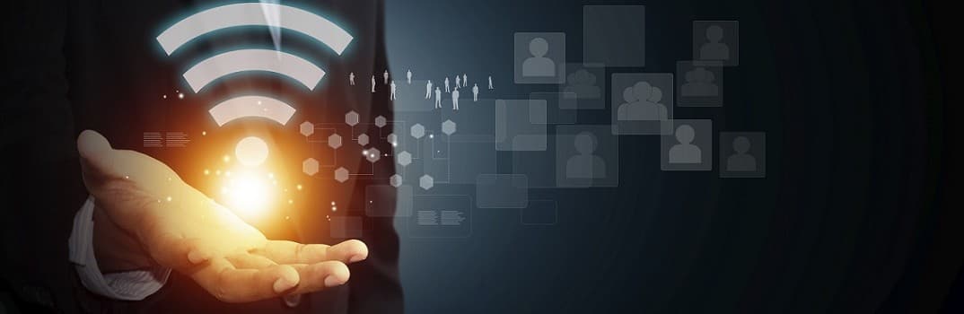 Man in a suit holding a glowing Wi-Fi symbol, with network graphics and profile icons in the background, symbolizing wireless connectivity and networking.