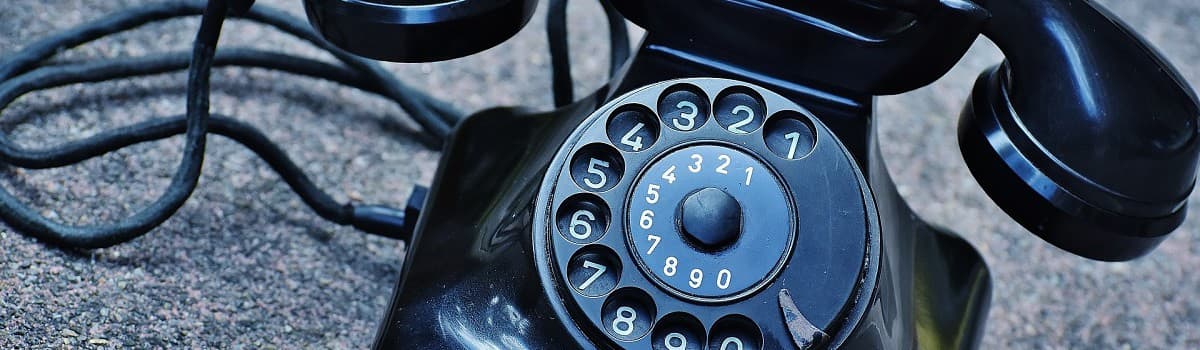 Close-up of a black vintage rotary telephone dial with numbers 0-9.