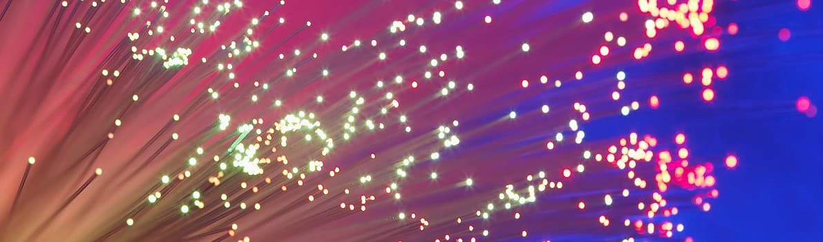 Bundle of fiber optic cables with colorful light streaks and glowing dots in pink, purple, and blue tones.